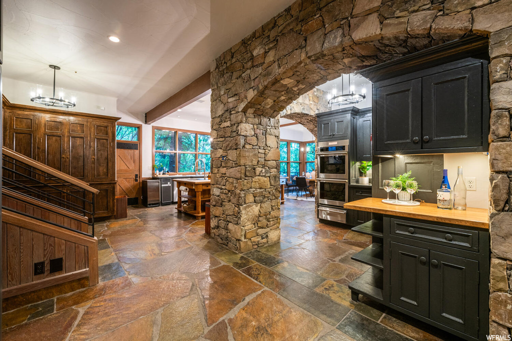 Kitchen with natural light, double oven, dark brown cabinetry, and dark tile floors