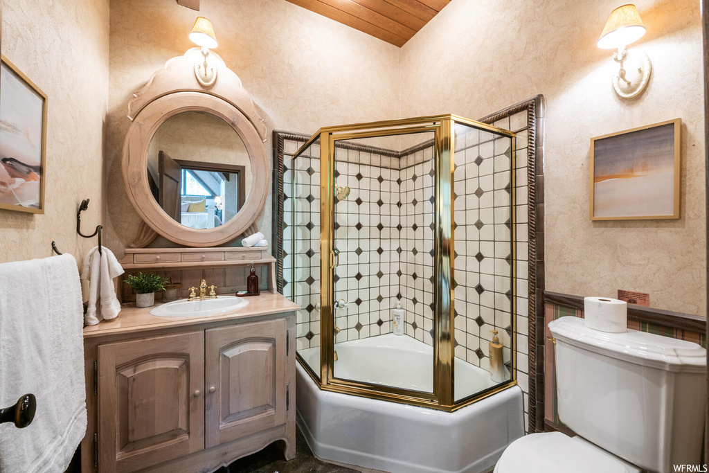 Full bathroom featuring toilet, enclosed tub / shower combo, mirror, and vanity