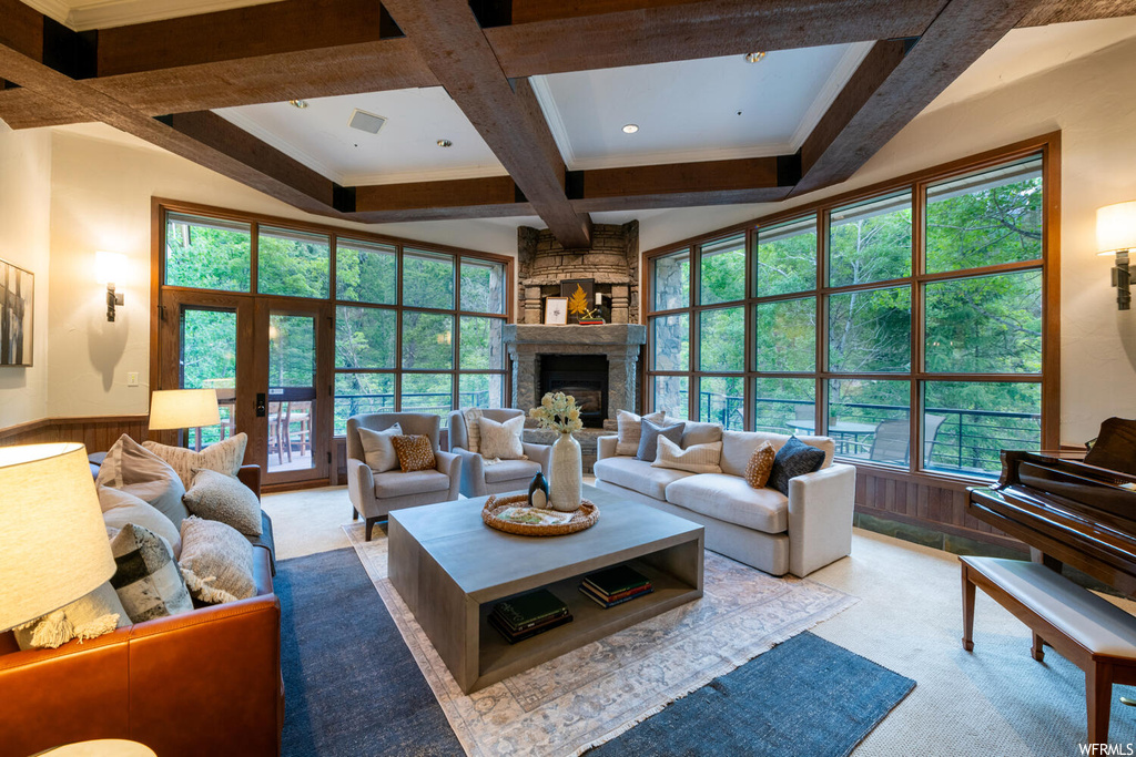 Carpeted living room with a fireplace, beamed ceiling, and a wealth of natural light