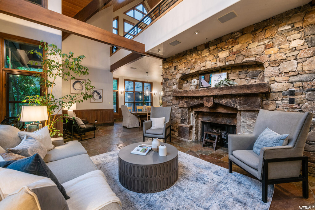 Living room featuring a fireplace, tile flooring, wood beam ceiling, and natural light