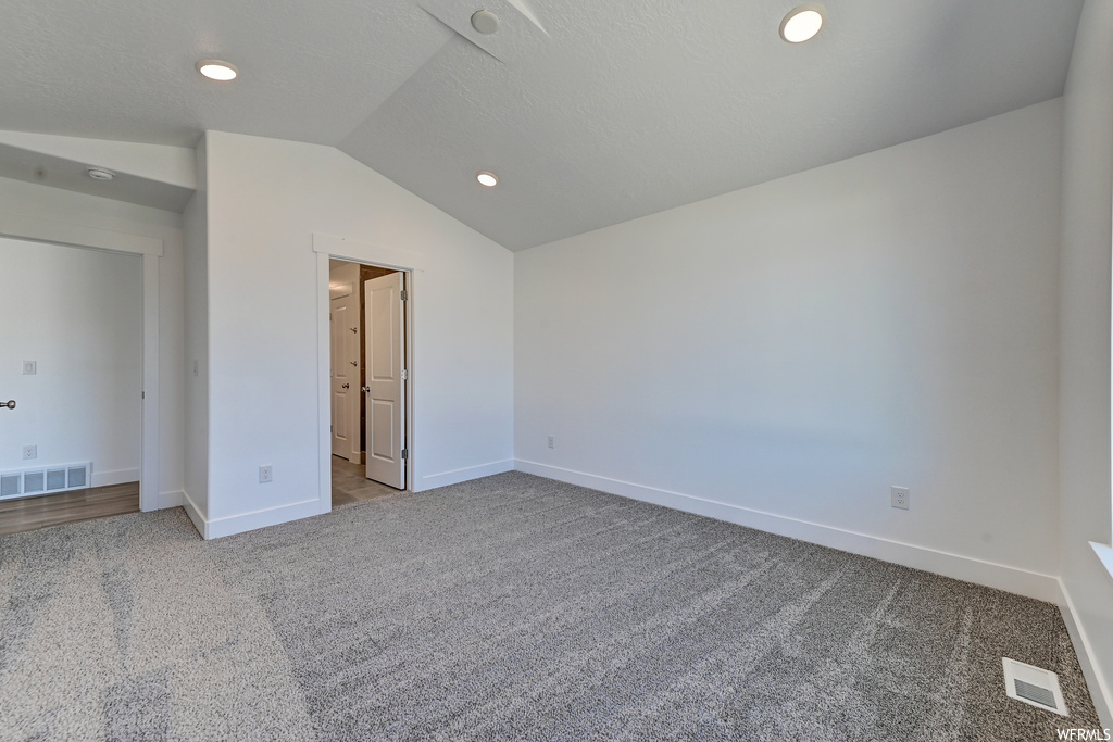 Unfurnished bedroom featuring light carpet and lofted ceiling