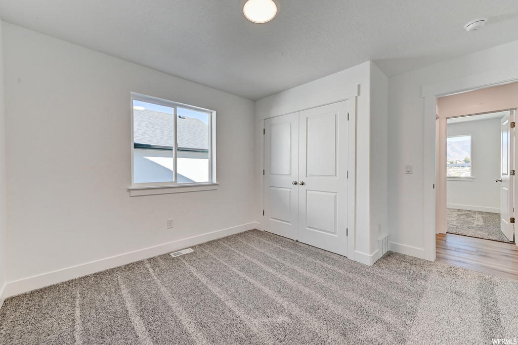 Unfurnished bedroom featuring light hardwood / wood-style flooring, multiple windows, and a closet