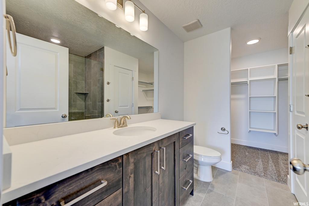 Bathroom with large vanity, toilet, and tile floors