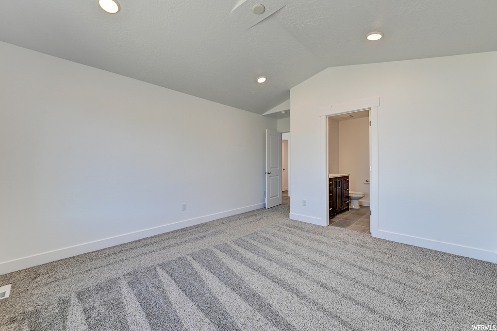 Empty room with lofted ceiling and light colored carpet