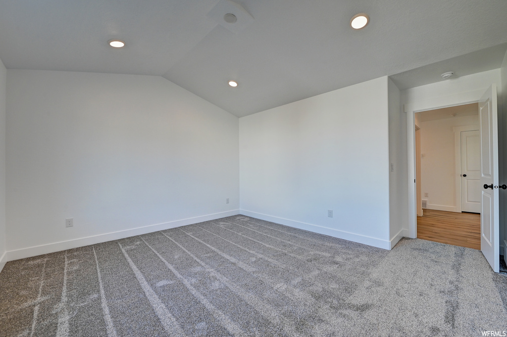 Empty room featuring carpet flooring and lofted ceiling