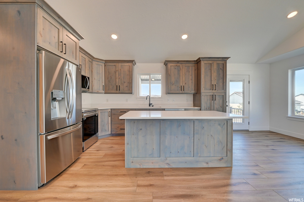 Kitchen with stainless steel appliances, a healthy amount of sunlight, and a center island