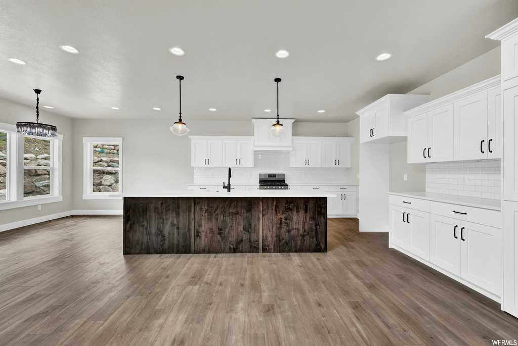 Kitchen with hardwood flooring, natural light, range oven, light countertops, pendant lighting, and white cabinetry