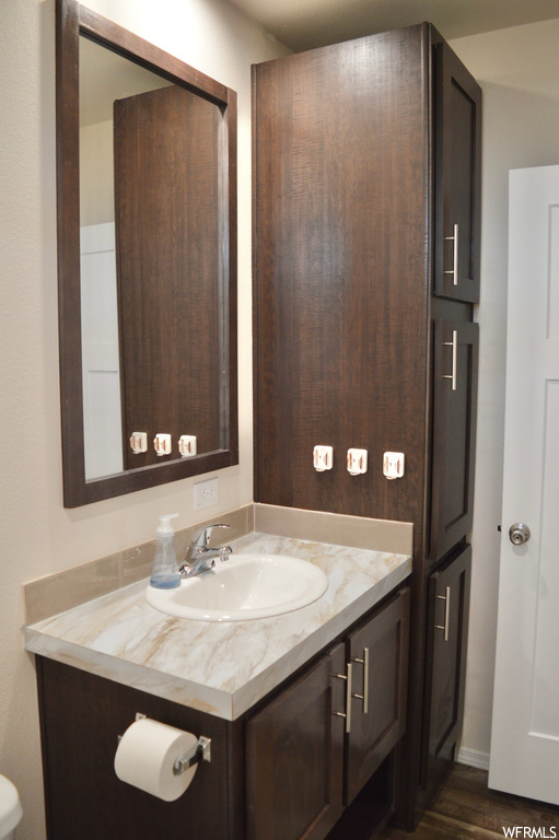 Bathroom with mirror, vanity, and dark hardwood flooring