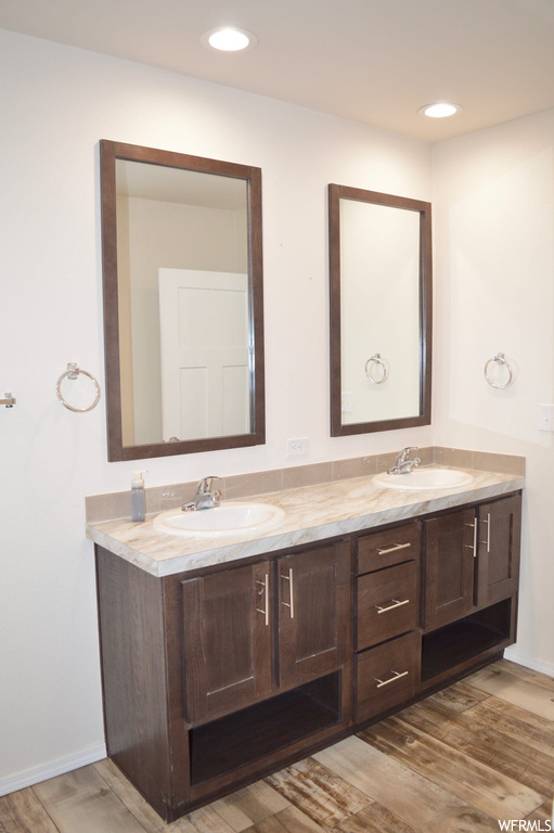 Bathroom featuring light hardwood flooring, mirror, and double vanity