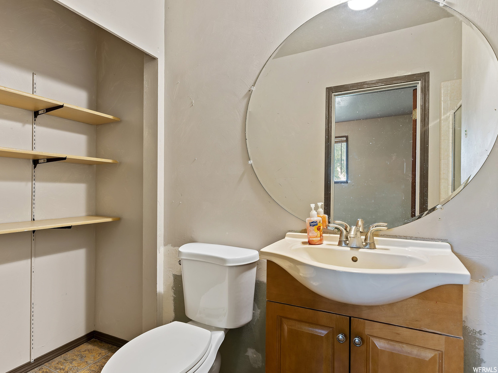 Half bathroom with toilet, mirror, and large vanity