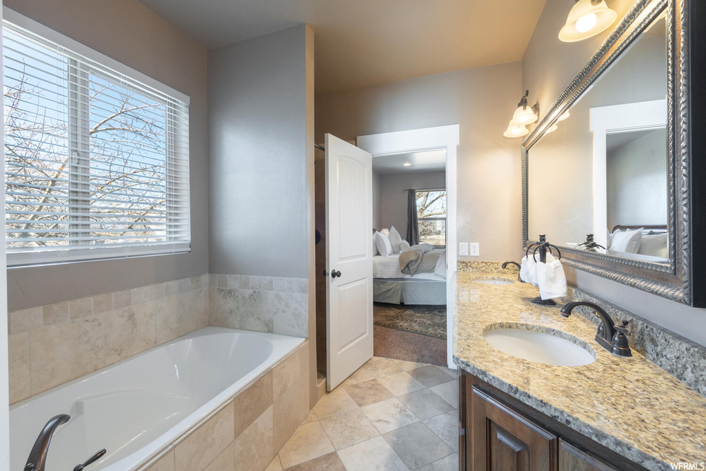 Bathroom featuring natural light, a bath, mirror, and double large vanity