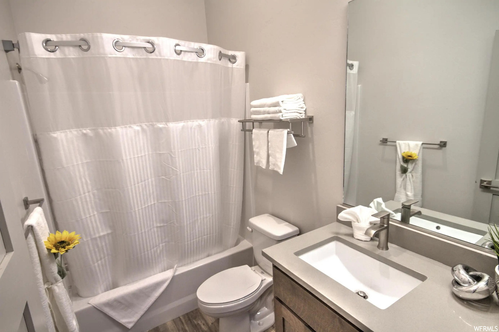 Full bathroom with mirror, vanity, washtub / shower combination, toilet, and shower curtain