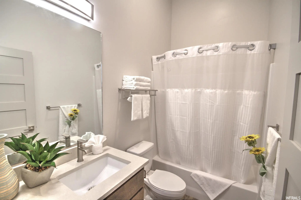 Full bathroom with multiple mirrors, shower / bathing tub combination, toilet, shower curtain, and vanity