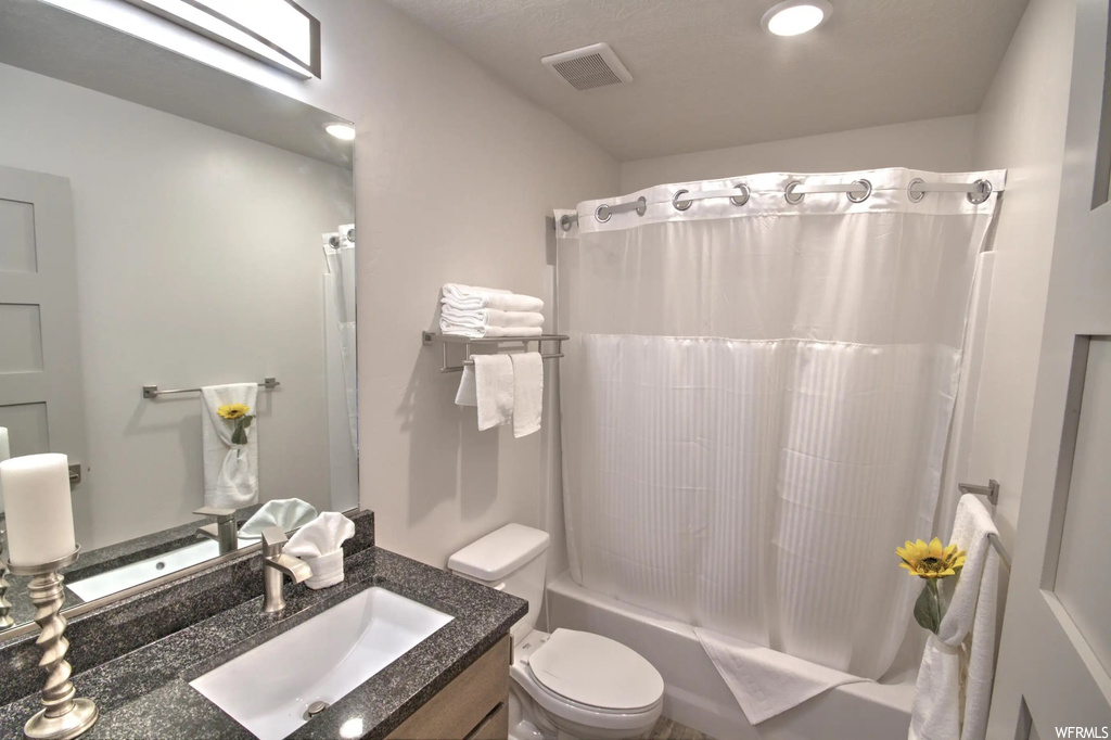 Full bathroom with mirror, vanity, toilet, shower / tub combination, and shower curtain