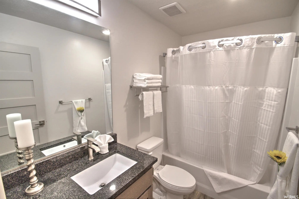 Full bathroom featuring shower / bathing tub combination, mirror, toilet, shower curtain, and vanity
