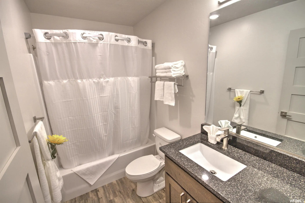 Full bathroom with mirror, toilet, vanity with extensive cabinet space, shower curtain, and shower / bath combination