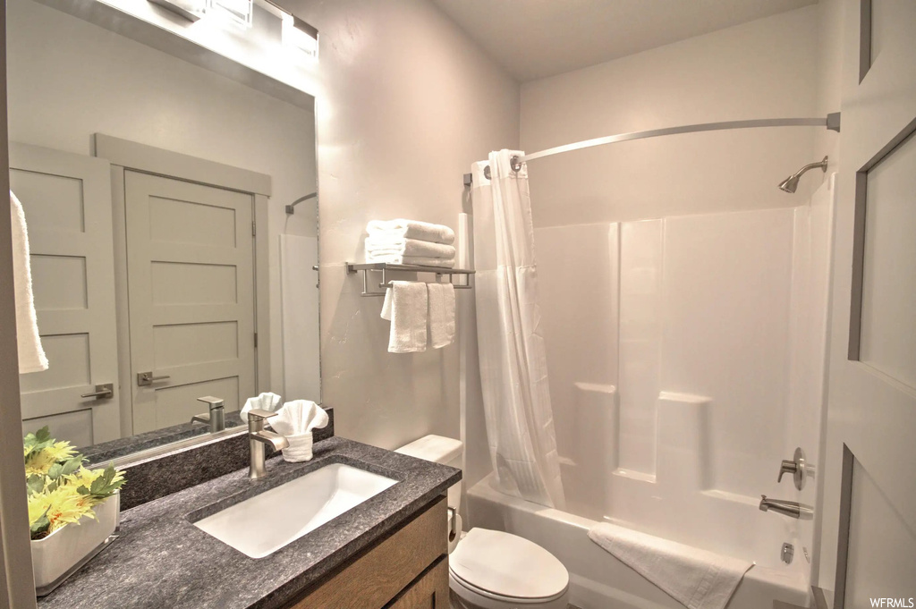 Full bathroom with multiple mirrors, shower / bathing tub combination, toilet, vanity with extensive cabinet space, and shower curtain