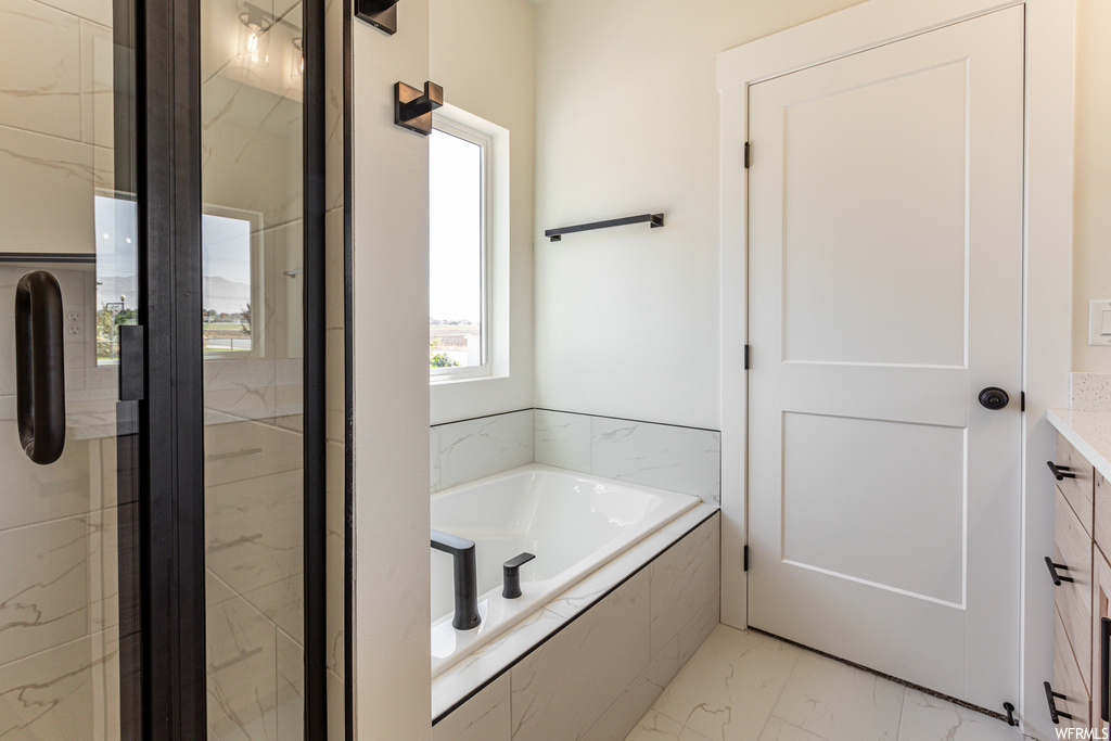 Bathroom featuring tile flooring, vanity, and shower with separate bathtub