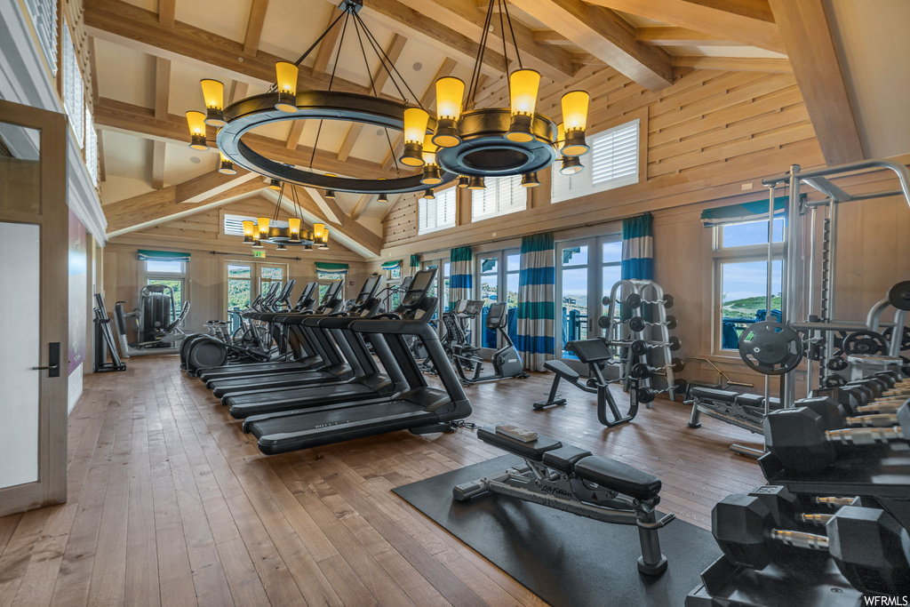 Workout area with hardwood floors, a high ceiling, wood beam ceiling, and natural light