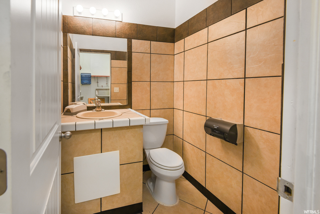 Half bath with tile flooring, toilet, mirror, and vanity