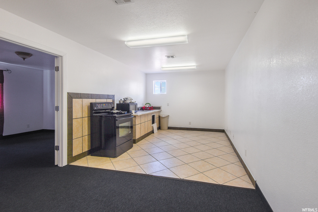 Kitchen with range oven and light tile flooring