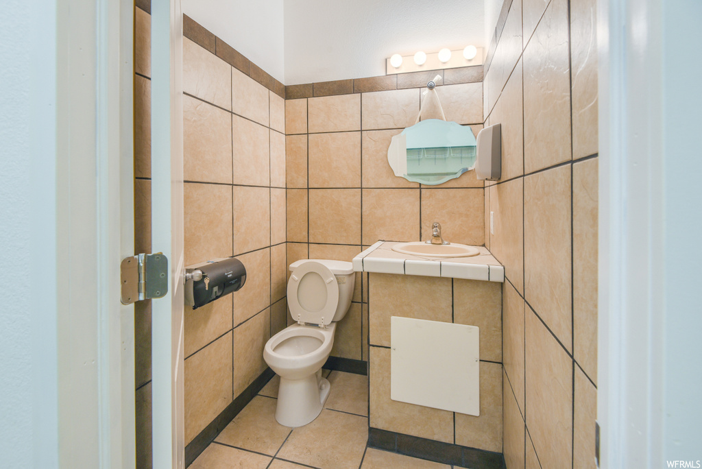 Half bathroom with tile floors, toilet, sink, and mirror