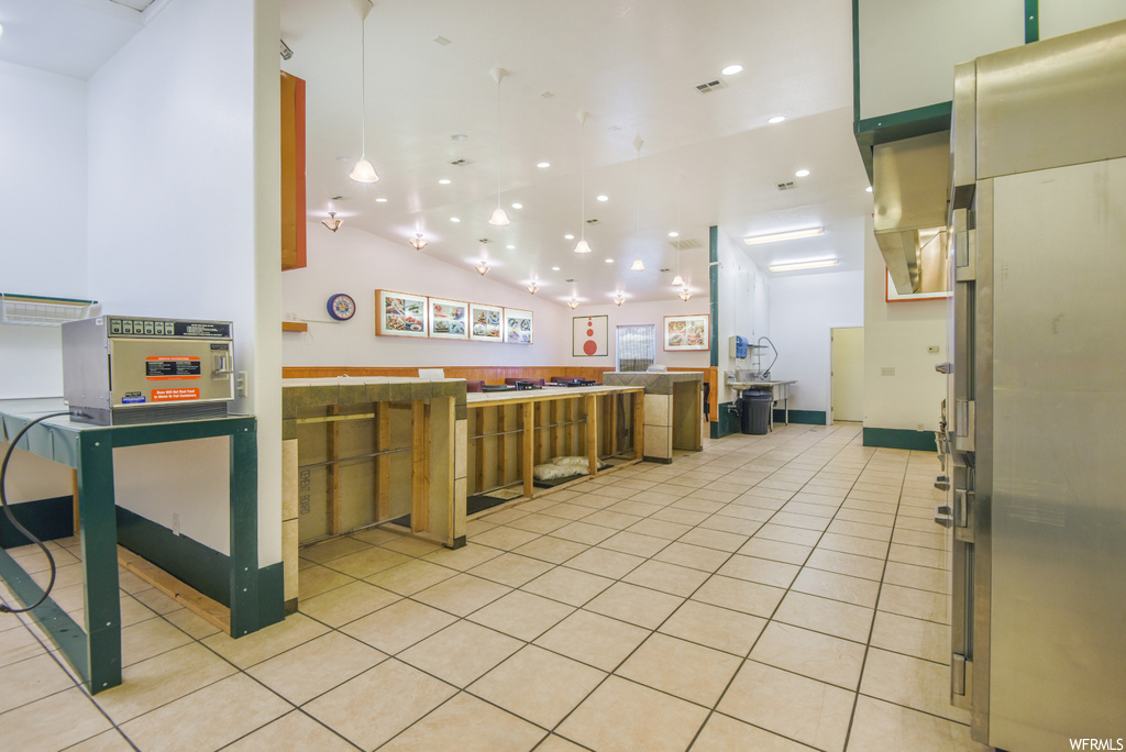 Kitchen with lofted ceiling, light tile flooring, light countertops, and pendant lighting