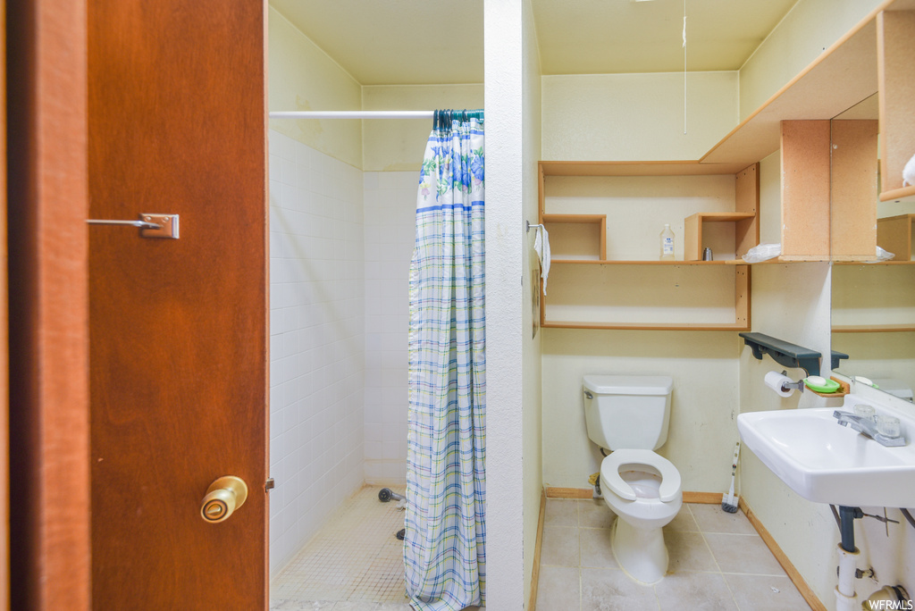Bathroom with tile floors, mirror, toilet, a shower, shower curtain, and washbasin