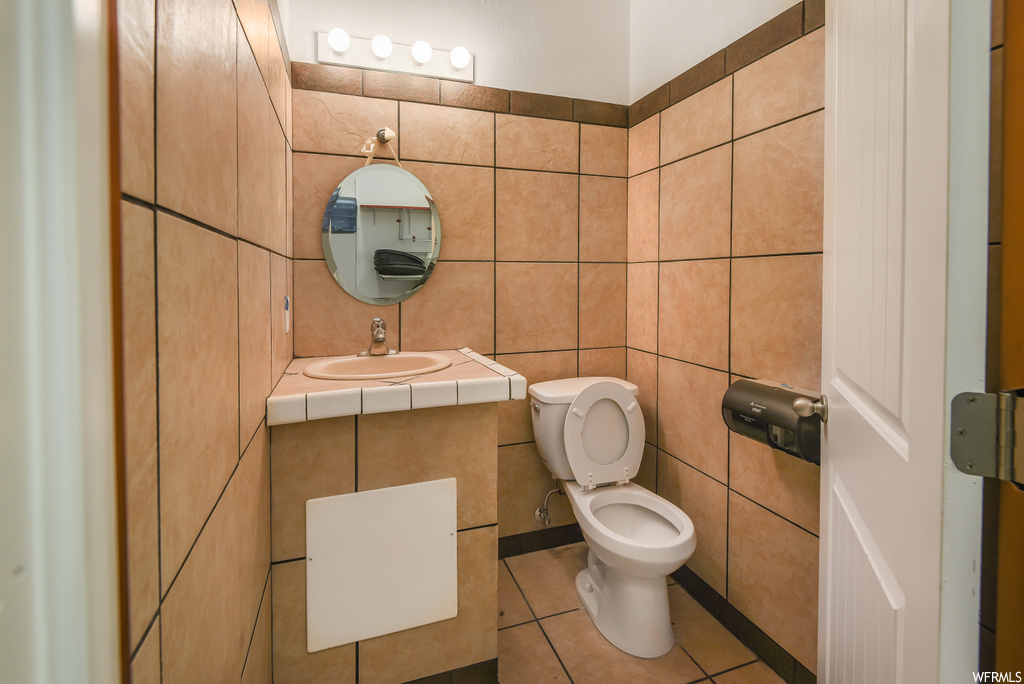 Half bath with tile flooring, toilet, mirror, and sink