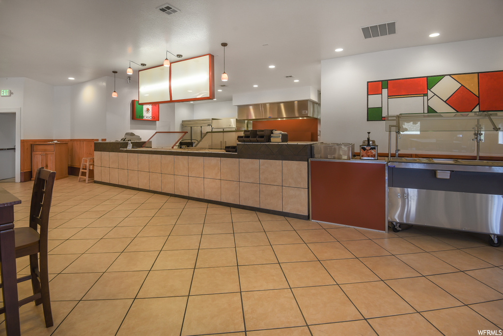 Kitchen with stainless steel finishes, light tile flooring, dark countertops, and pendant lighting