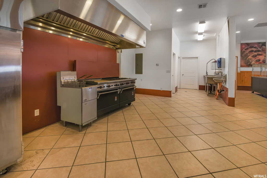 Kitchen with stainless steel finishes, light tile flooring, and dark countertops