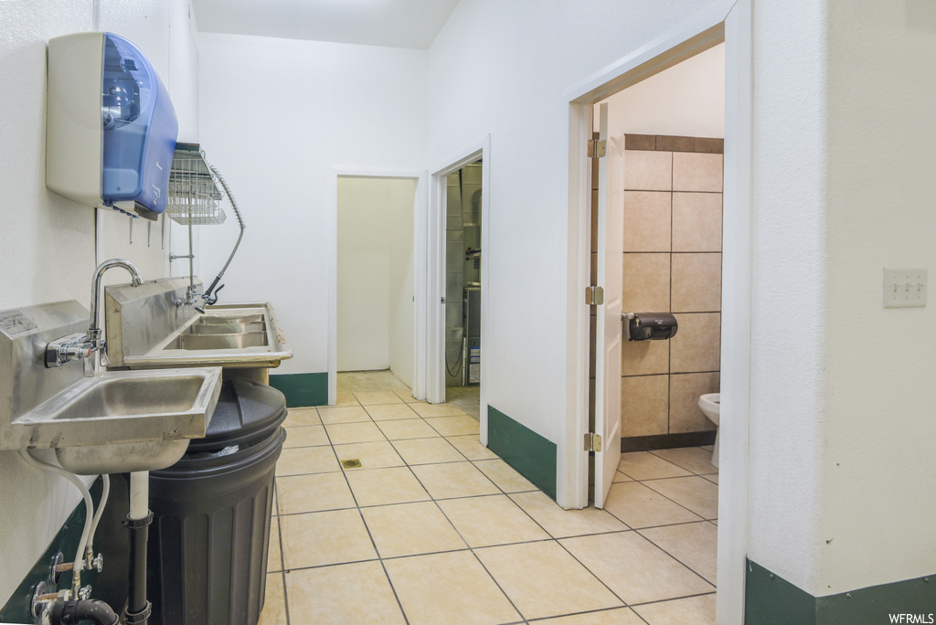 Bathroom with tile floors, toilet, his and her sinks, and mirror