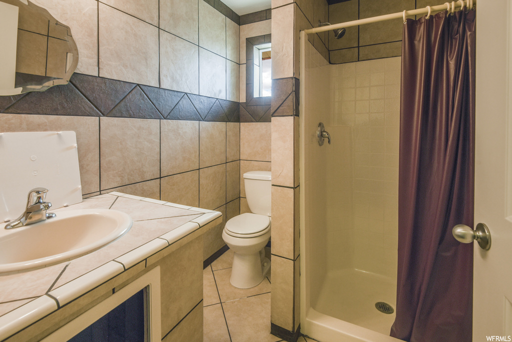 Bathroom featuring tile floors, mirror, toilet, a shower, shower curtain, and vanity