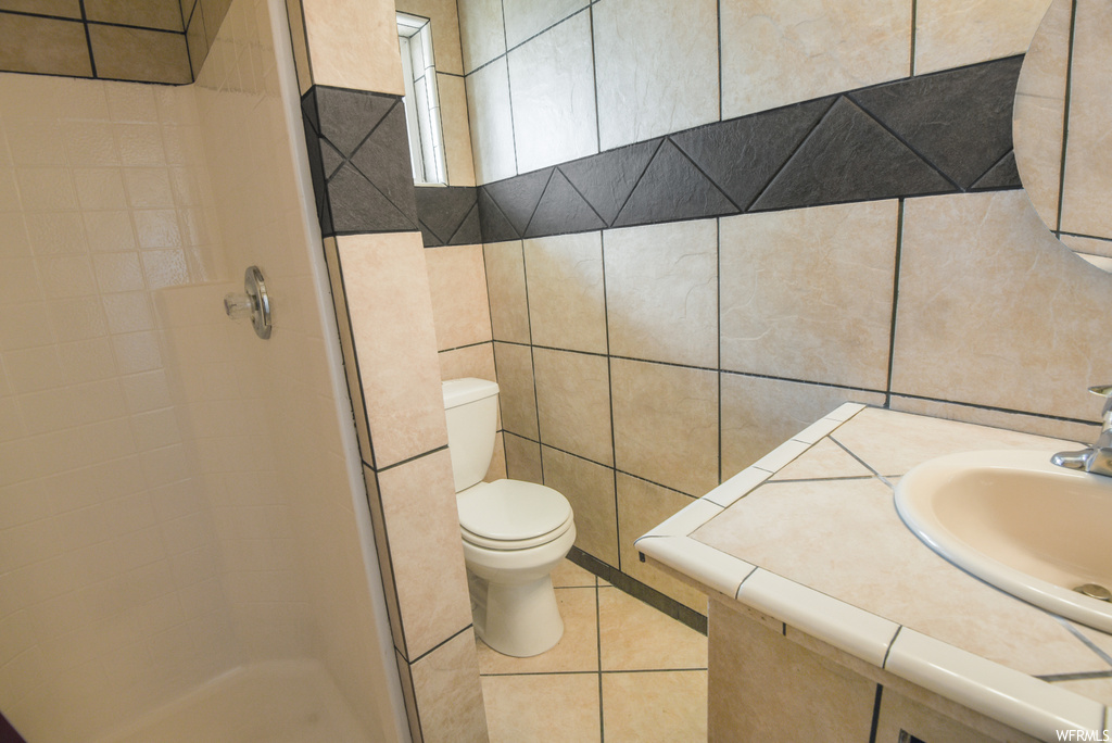 Bathroom with tile flooring, toilet, sink, and a shower