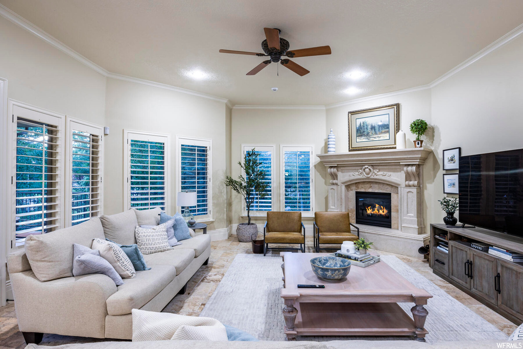 Living room with ceiling fan, plenty of natural light, a high end fireplace, and crown molding