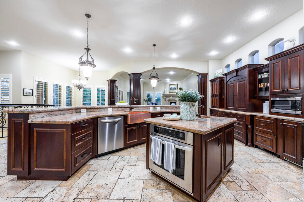 Kitchen with a center island, pendant lighting, stainless steel appliances, and light tile floors