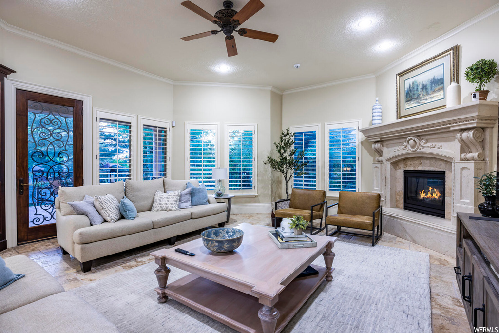 Tiled living room featuring a fireplace, ceiling fan, and ornamental molding