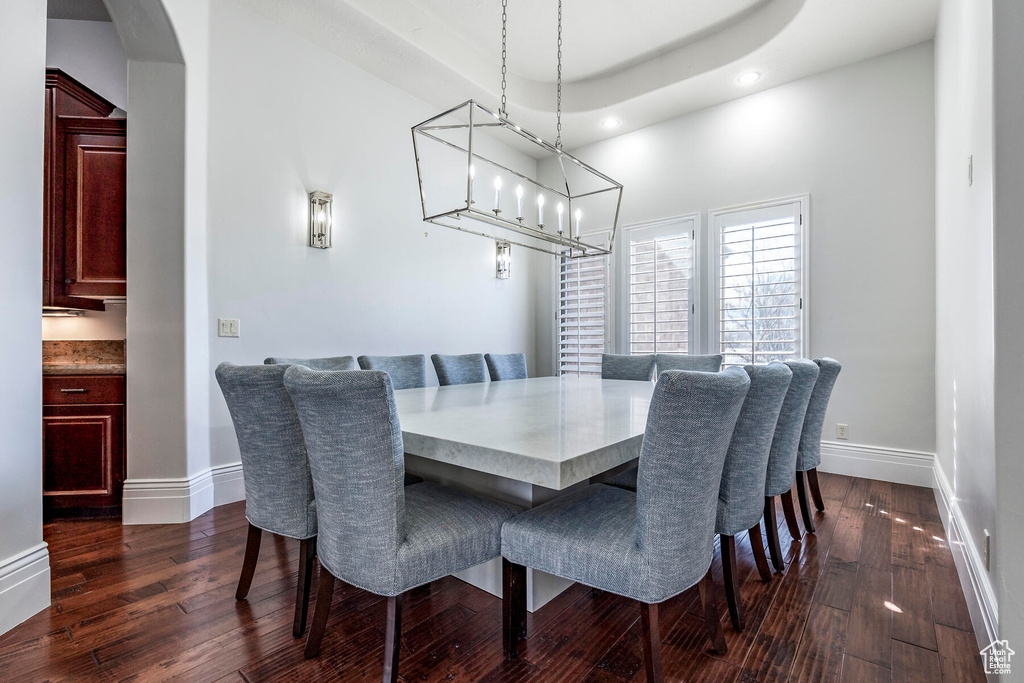 Dining space featuring a tray ceiling, an inviting chandelier, and dark hardwood / wood-style flooring