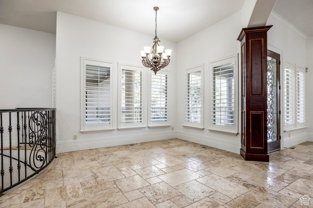 Unfurnished room featuring light tile floors, a chandelier, and ornamental molding