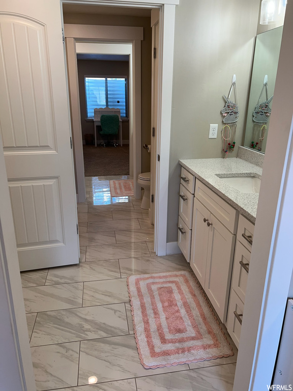 Half bath featuring tile flooring, toilet, mirror, and vanity