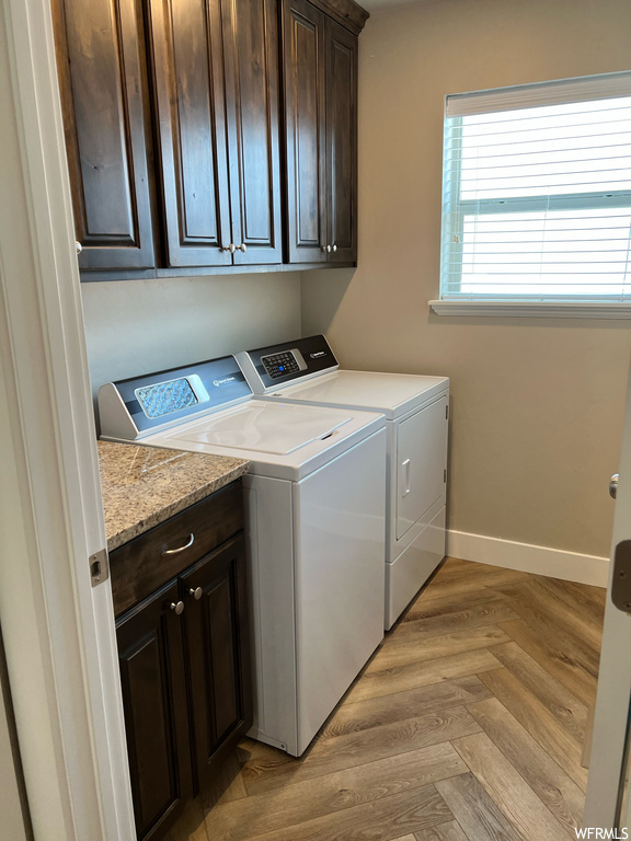 Laundry room with hardwood flooring, natural light, and independent washer and dryer