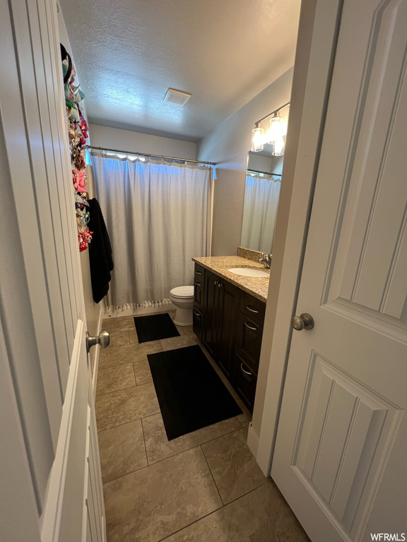 Bathroom featuring tile flooring, toilet, mirror, oversized vanity, and shower curtain