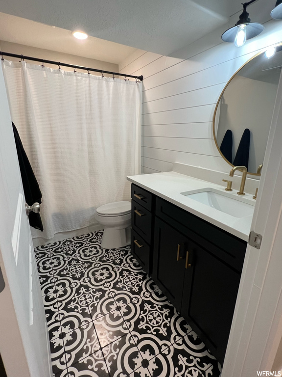Bathroom with toilet, shower curtain, mirror, and vanity