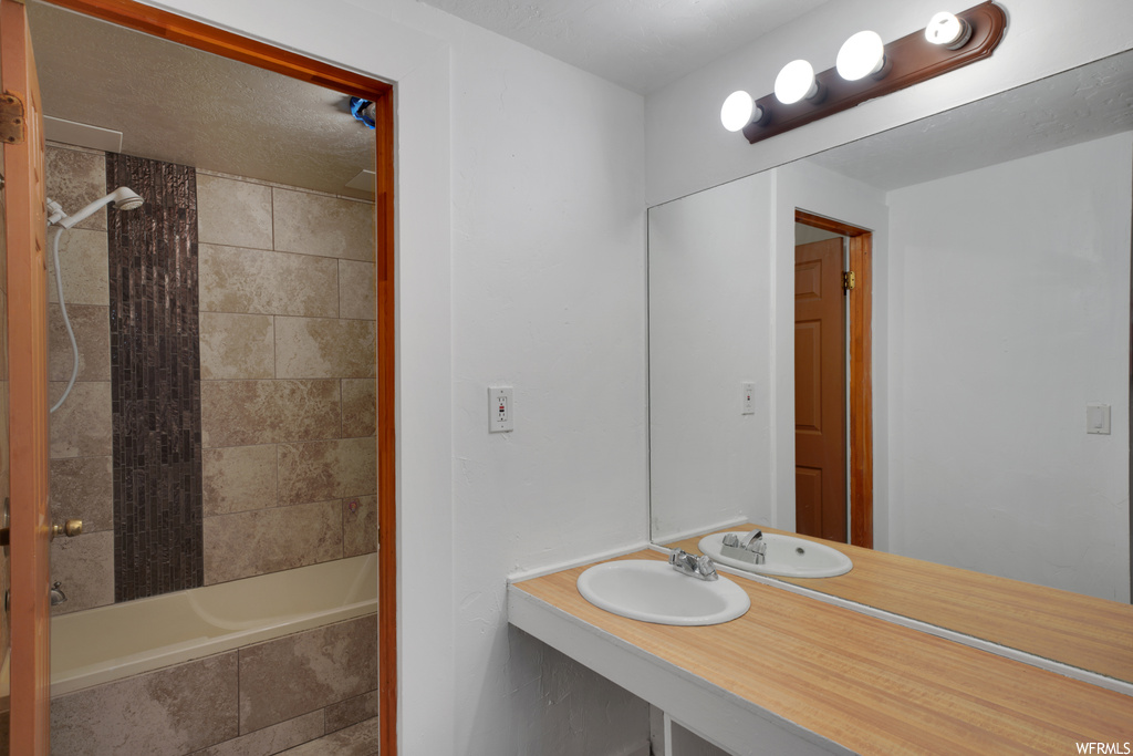 Bathroom featuring large vanity, mirror, and tub / shower combination