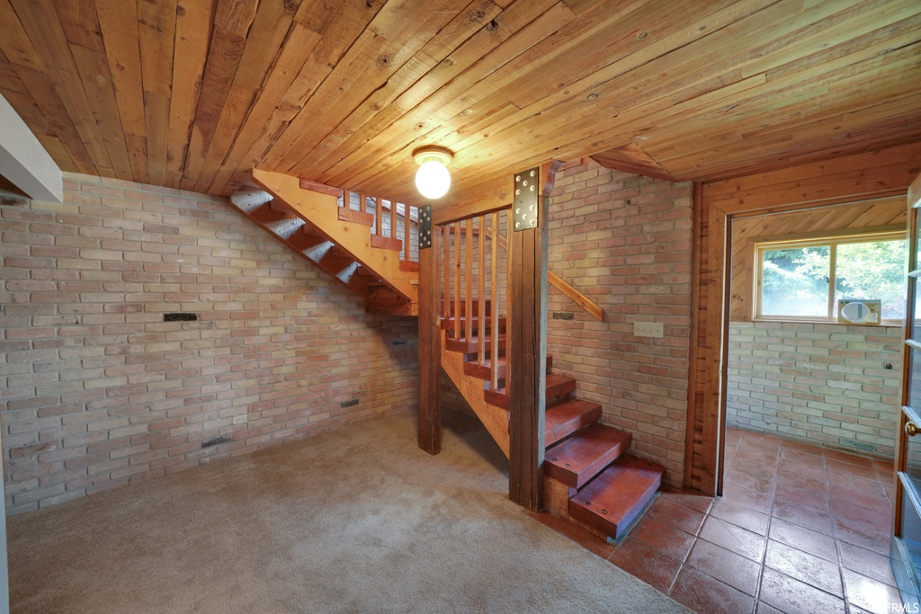 Basement featuring natural light, carpet, and exposed bricks