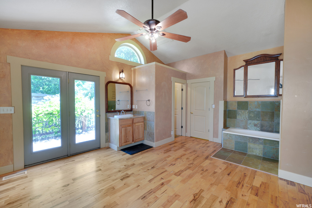 Interior space featuring vaulted ceiling, natural light, a ceiling fan, and light tile floors
