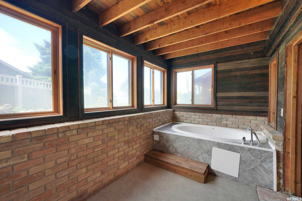 Bathroom with natural light, exposed bricks, and a tub