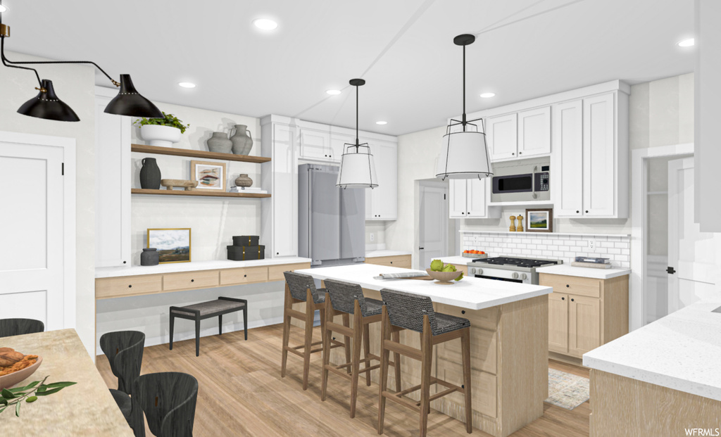 Kitchen with a breakfast bar, a kitchen island, microwave, range oven, white cabinets, pendant lighting, light countertops, and light hardwood flooring