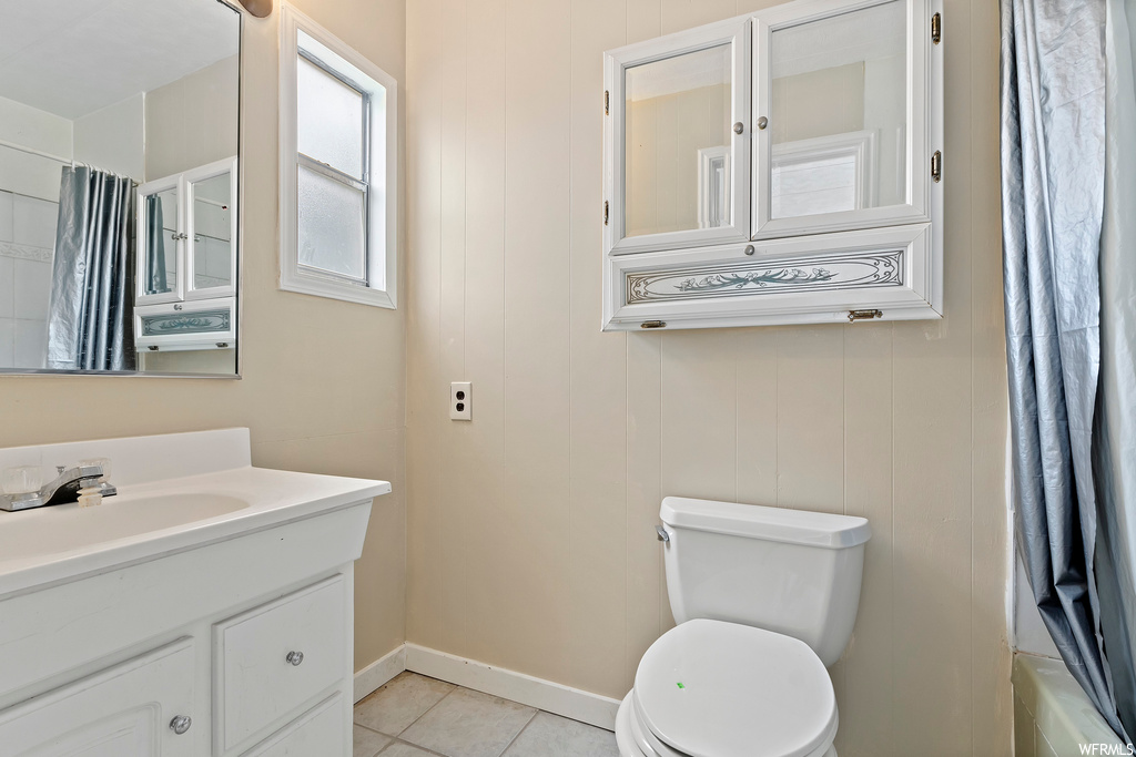 Bathroom featuring tile flooring, toilet, shower curtain, mirror, and vanity