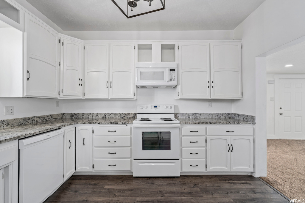 Kitchen with microwave, dishwasher, electric range oven, white cabinets, dark floors, and light countertops